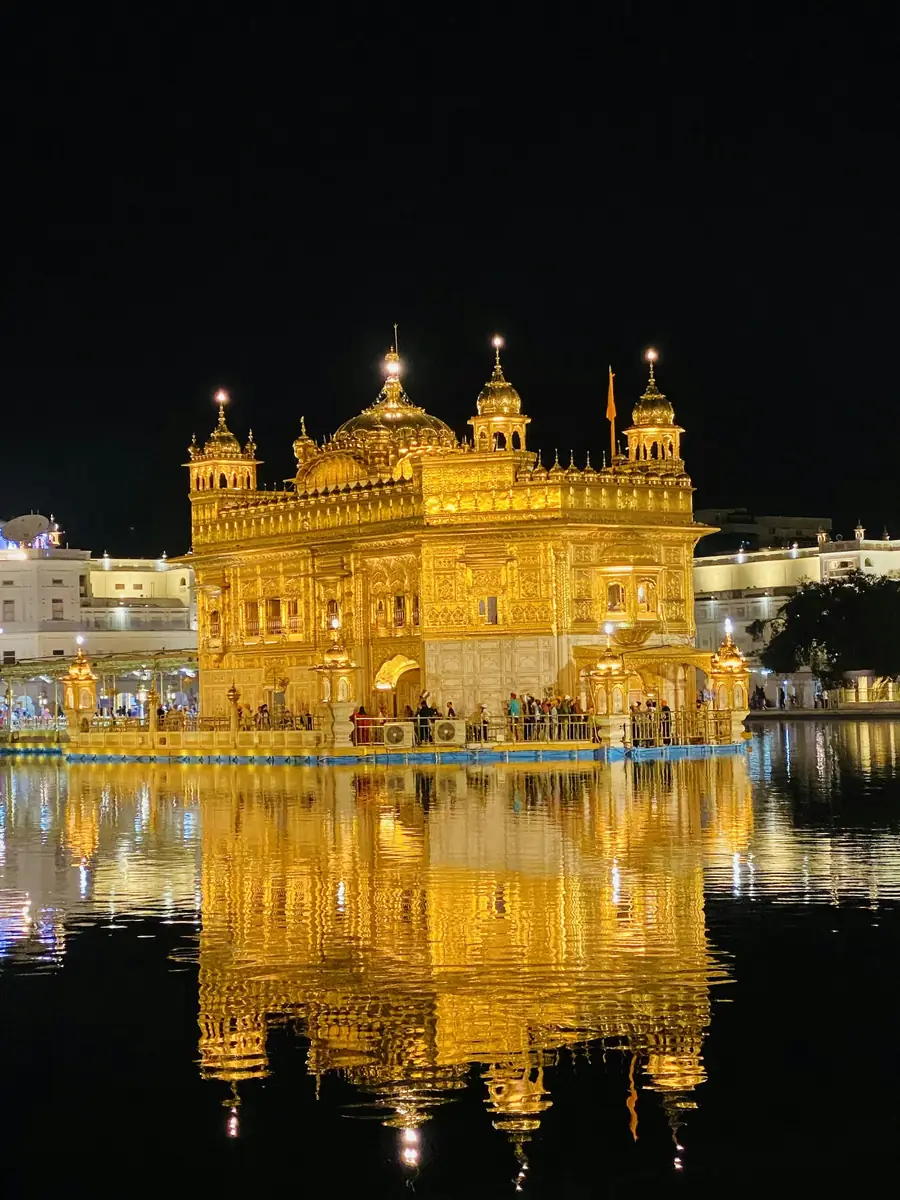 Harmandir Sahib (the Golden Temple) in Amritsar lit gold at night, reflected in the sarovar